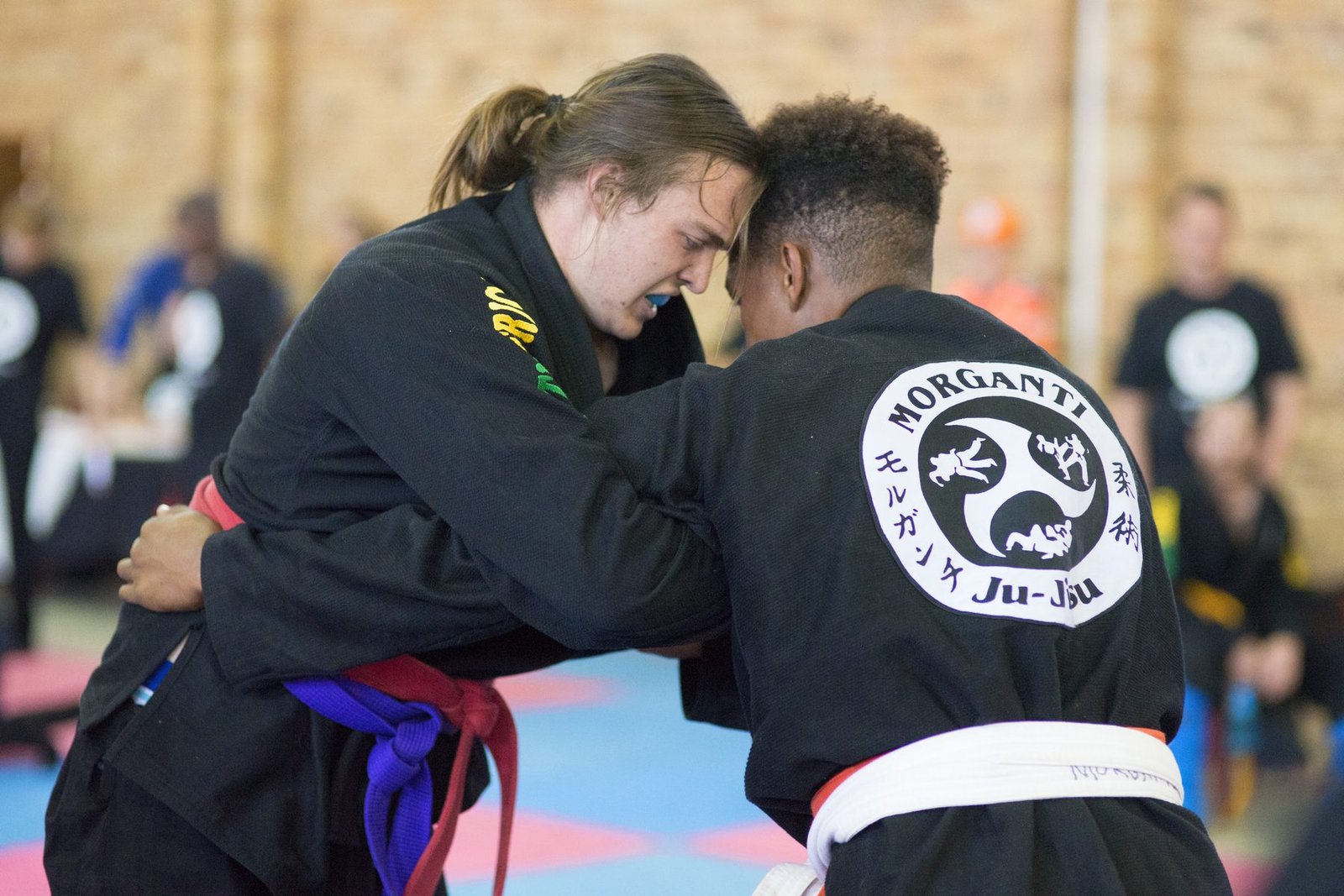 Dois atletas de kimono preto em disputa de pegada; nas costas de um deles, o bordado do logo Morganti Ju-Jitsu